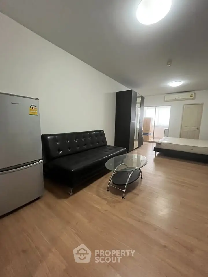 Spacious studio apartment with modern furnishings and wooden flooring.