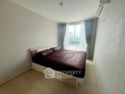 Spacious bedroom with large window and modern furnishings in a high-rise apartment.