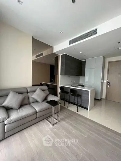 Modern living room with sleek kitchen and stylish sofa in open layout apartment.
