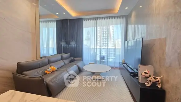 Luxurious modern living room with sleek leather sofa and large TV, offering a stunning city view.