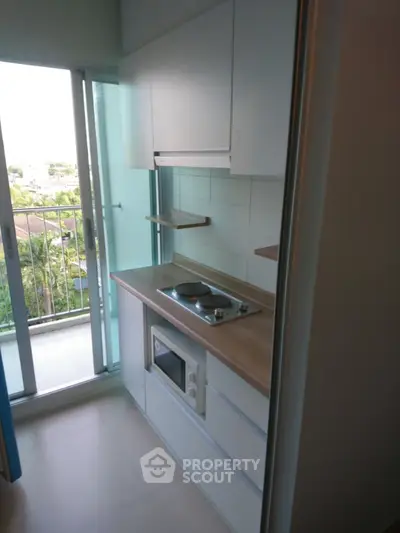Compact kitchen with modern appliances and balcony view