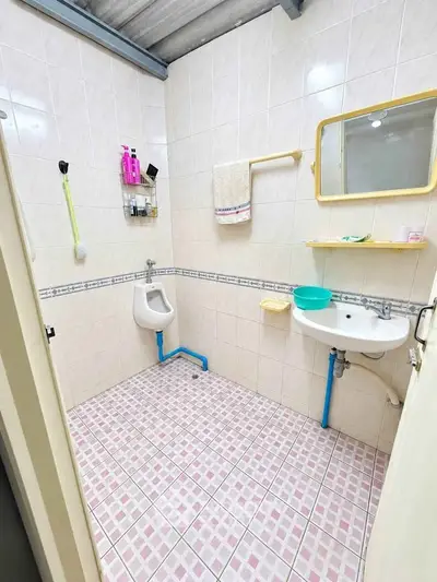 Spacious bathroom with tiled walls and floor, featuring a urinal and sink, ideal for modern living.