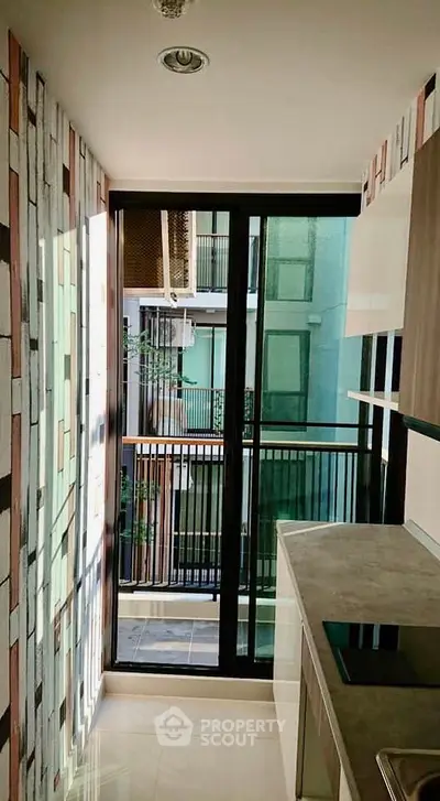 Modern kitchen with sleek design and large windows offering natural light and balcony view.