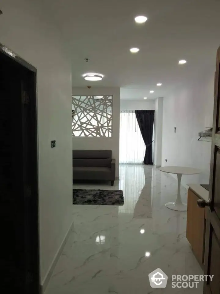 Modern living room with sleek design and marble flooring, featuring a stylish partition and natural light.