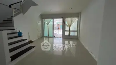 Spacious living room with large windows and staircase, perfect for modern living.