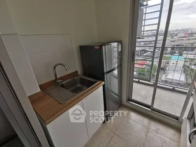 Compact kitchen with balcony view and modern appliances in urban apartment