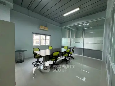 Modern office space with glass partitions and sleek design, featuring a conference table and ergonomic chairs.