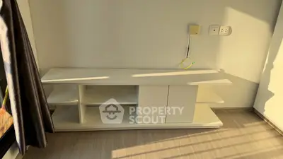 Modern minimalist white TV stand in sunlit room with wooden flooring