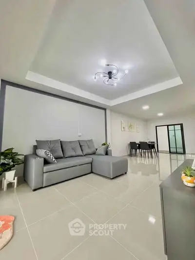 Spacious modern living room with sleek gray sofa and elegant dining area, perfect for contemporary living.