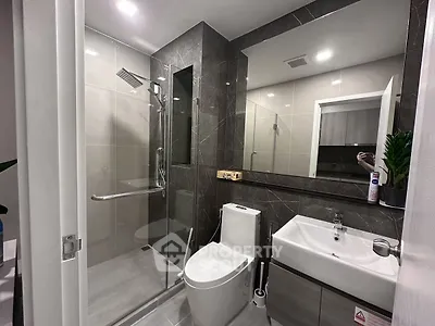 Modern bathroom with glass shower and sleek fixtures in contemporary apartment.