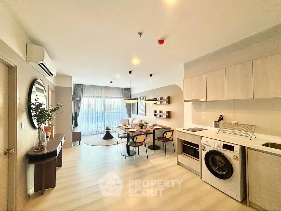 Modern open-plan living room with dining area and kitchen featuring sleek appliances.