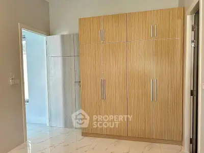 Spacious bedroom with built-in wooden wardrobe and sleek tile flooring