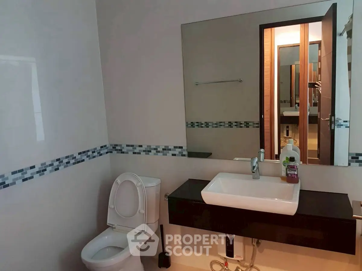 Modern bathroom with sleek sink and toilet, featuring stylish tile accents.