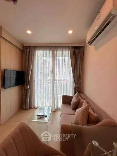 Cozy living room with modern decor, featuring a wall-mounted TV and a comfortable sofa near a large window.