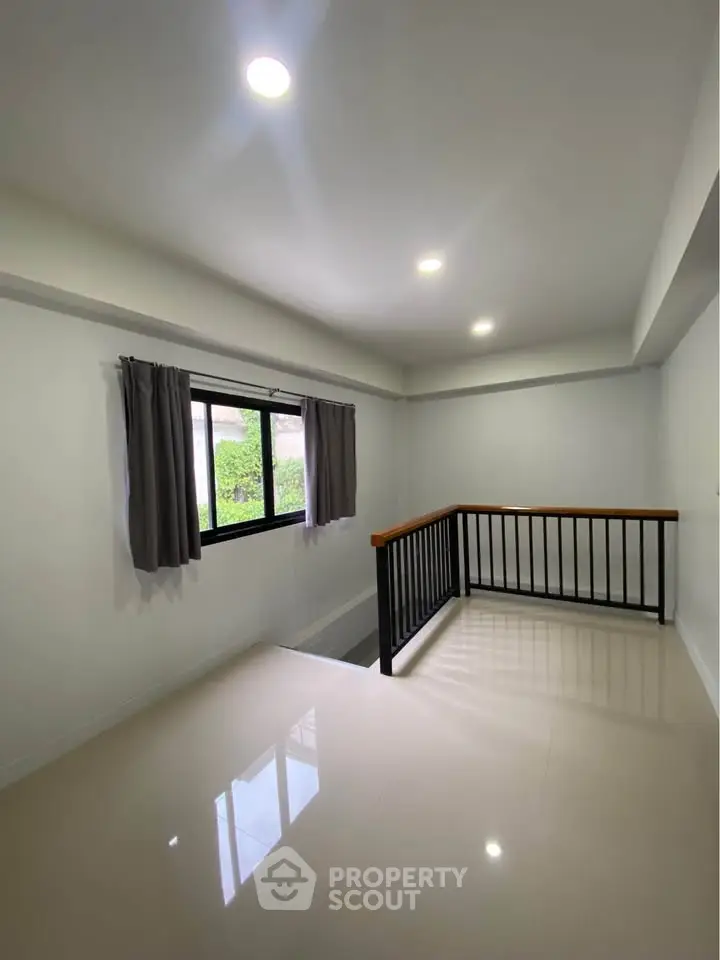 Bright and spacious interior with modern railing and large window, perfect for a cozy living space.