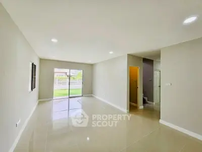 Spacious modern living room with large windows and garden view, perfect for family gatherings.