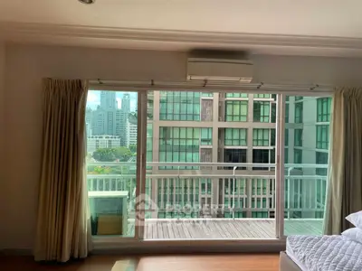Spacious bedroom with balcony offering city view and natural light