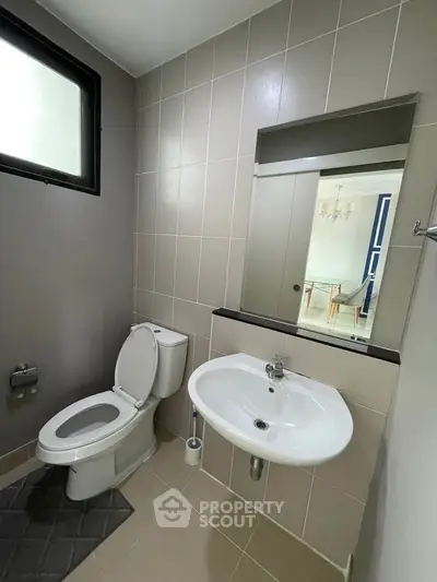 Modern bathroom with sleek design and neutral tones, featuring a toilet and sink.