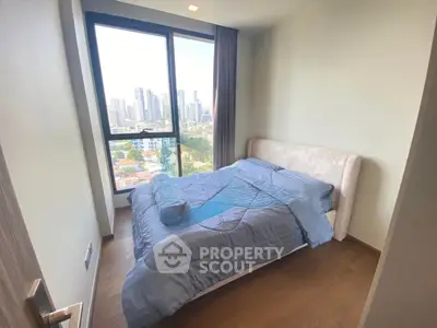 Cozy bedroom with city view and large window in modern apartment