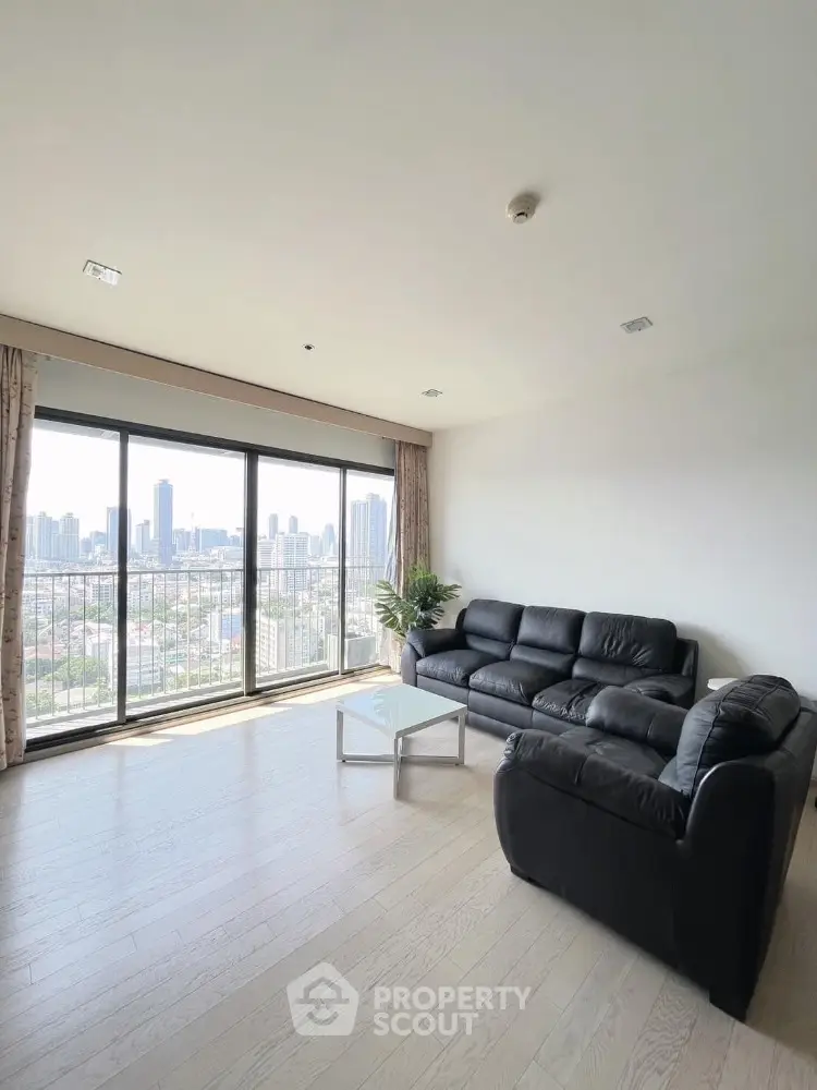 Spacious living room with city view and modern black leather sofas