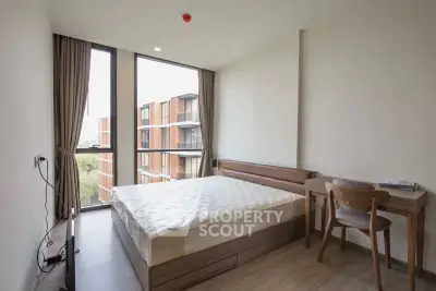 Modern bedroom with large window and stylish furniture in a contemporary apartment.