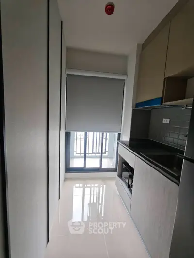 Modern compact kitchen with sleek cabinetry and large window for natural light