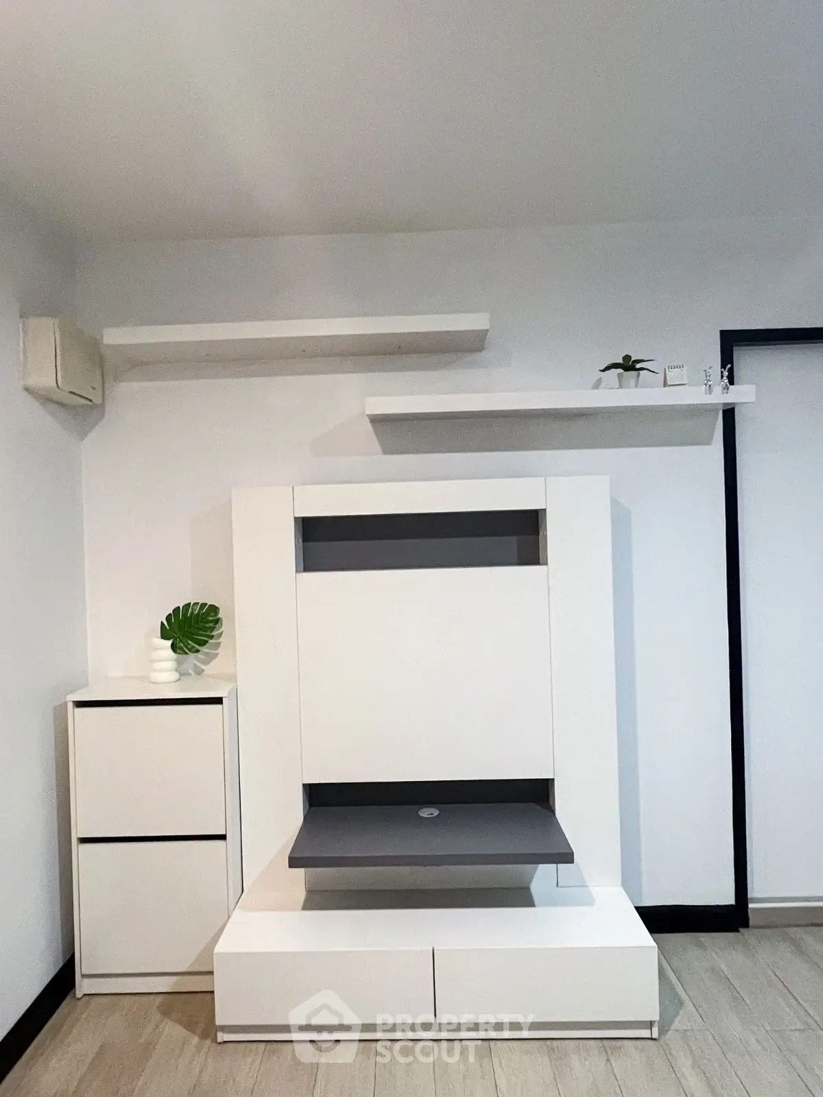 Modern minimalist living room with sleek white furniture and decorative shelves.