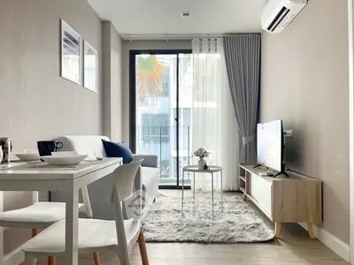 Modern living room with stylish decor and natural light, featuring cozy seating and a sleek TV setup.