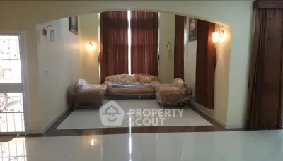 Spacious living room with high ceilings and elegant lighting, featuring a cozy sofa set and large windows.