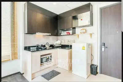 Modern compact kitchen with sleek cabinets and built-in appliances in a stylish apartment.
