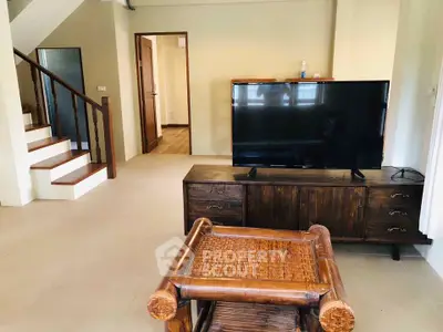 Spacious living room with modern TV setup and elegant wooden furniture.
