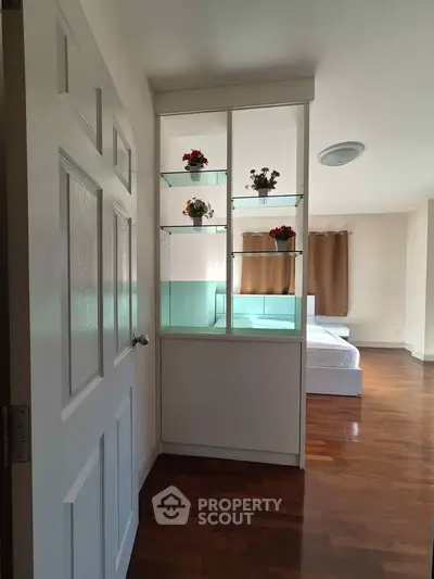 Spacious bedroom with elegant wooden flooring and decorative shelving