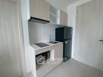 Modern compact kitchen with sleek cabinetry and built-in appliances in a minimalist apartment.