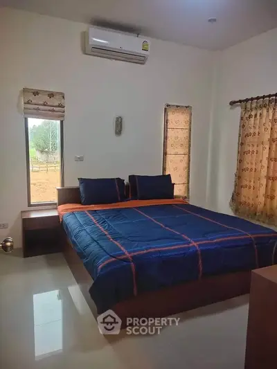 Cozy bedroom with modern decor and air conditioning, featuring a large bed and natural light.