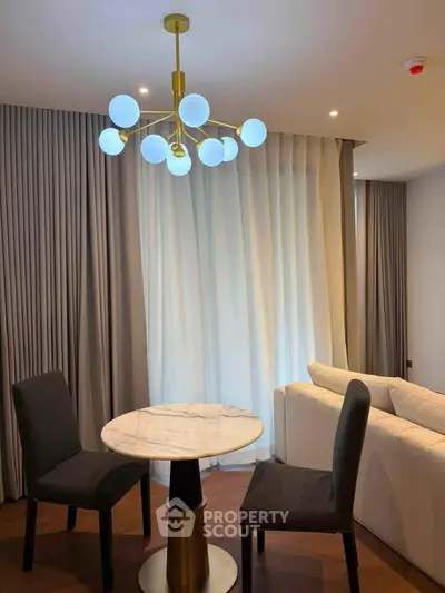 Elegant living room with modern chandelier and cozy seating area, perfect for relaxation and entertaining.