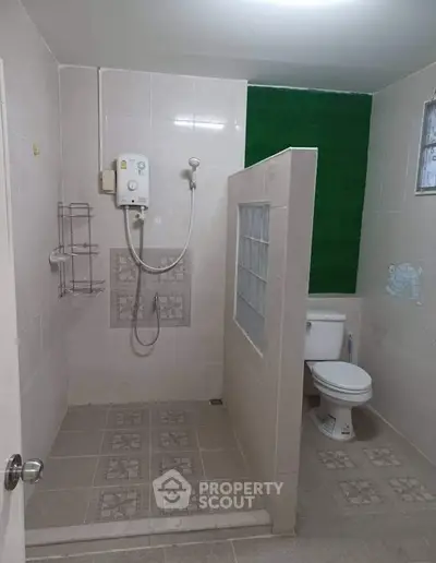 Spacious bathroom with modern shower and toilet in a stylish tiled setting.