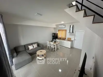 Modern open-plan living room with sleek furniture and staircase, perfect for contemporary living.