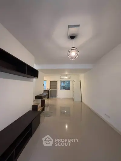 Spacious living room with modern lighting and sleek shelving in a minimalist design.