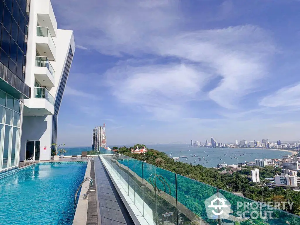 Luxurious infinity pool with panoramic sea view, adjacent to a modern high-rise, under a clear blue sky, perfect for upscale living.