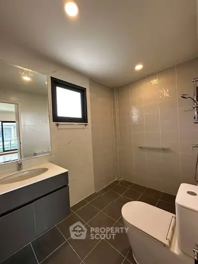 Modern bathroom with sleek fixtures and large mirror in contemporary apartment.
