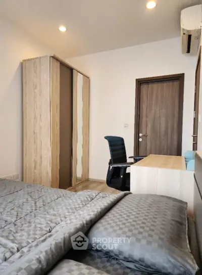Modern bedroom with stylish furniture and cozy ambiance, featuring a sleek wardrobe and comfortable workspace.
