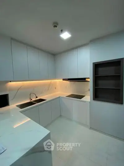 Modern kitchen with sleek white cabinetry and under-cabinet lighting in a contemporary apartment.
