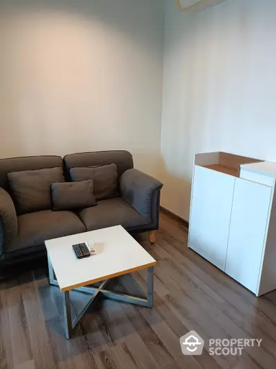 Cozy living room with modern furniture, featuring a comfortable brown sofa and a stylish white coffee table on elegant hardwood flooring.