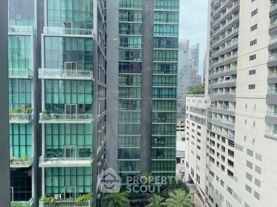 Modern high-rise buildings with glass facades and lush greenery in urban setting.