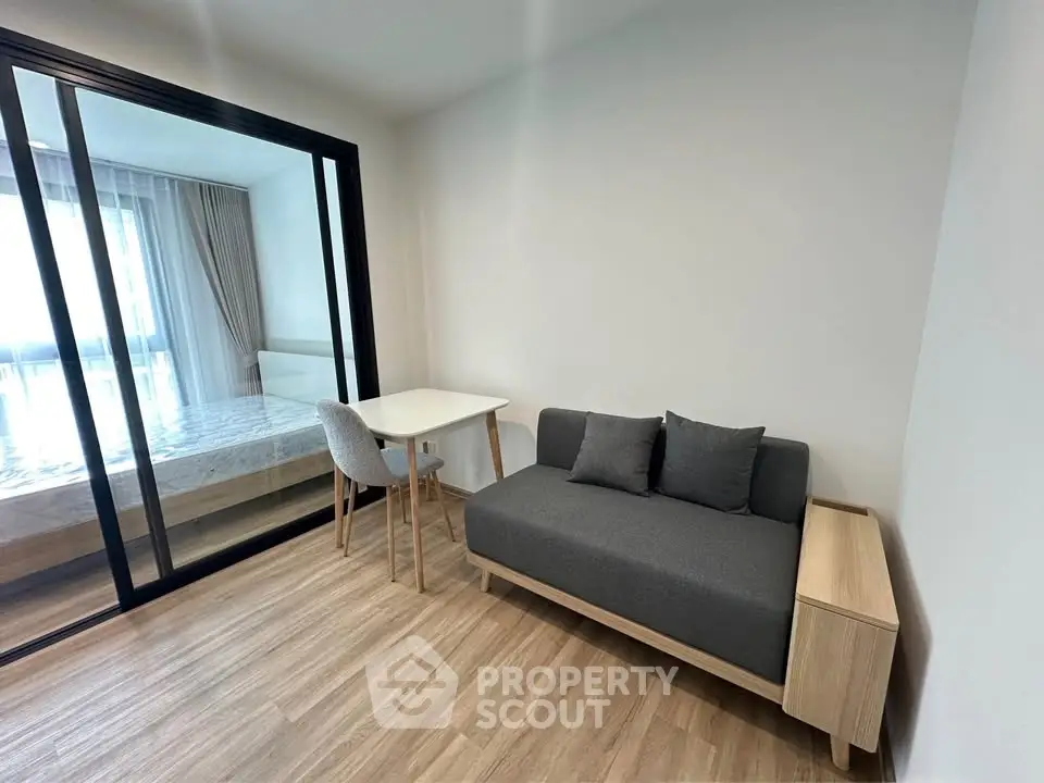 Modern studio apartment with cozy living area and bedroom separated by glass partition.