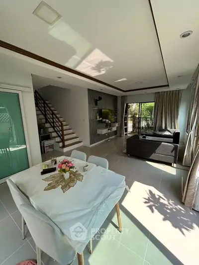 Spacious modern living room with dining area and natural light, featuring elegant decor and garden view.
