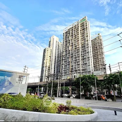 Modern high-rise building with lush greenery and clear blue sky