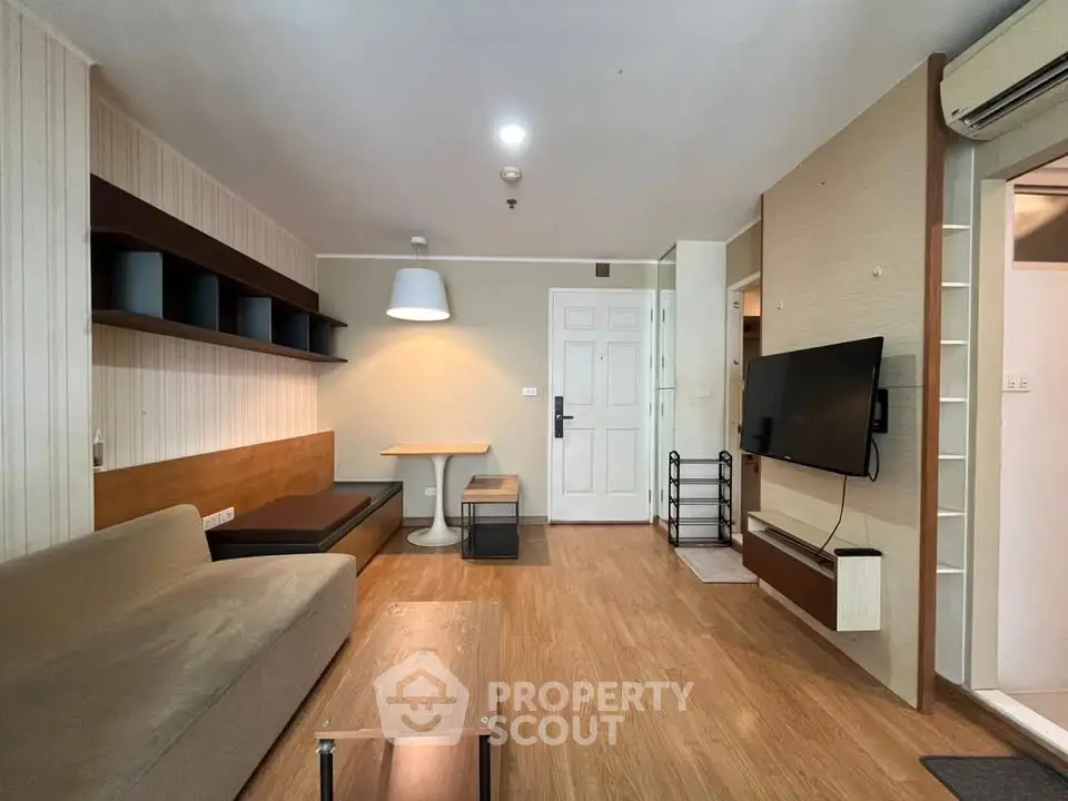 Modern living room with stylish decor and wooden flooring, featuring a wall-mounted TV and cozy seating area.