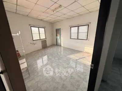 Spacious empty room with tiled floor and large windows, ideal for customization.
