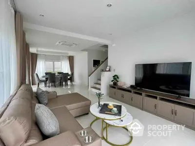 Spacious modern living room with sectional sofa and large TV, open to dining area.